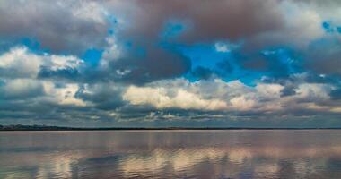 The bottom of the dried-up Kuyalnitsky estuary, covered with a layer of white self-precipitating table salt, clouds are reflected in the water photo