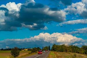 White cumulus thunderclouds in the sky over a highway, Ukraine photo