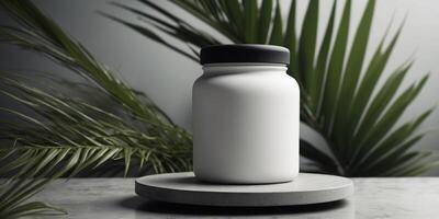 White cream jar with black lid on a concrete podium with a green palm leaf in the background. photo
