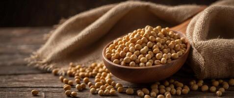 Soybeans in a wooden spoon on a rustic wooden table with a burlap sack in the background. photo