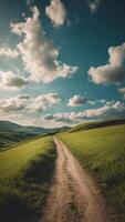 Path on a lush green hill under a sunny sky with clouds. photo
