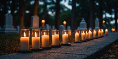 A row of candles are lit on a path in front of a cemetery. photo