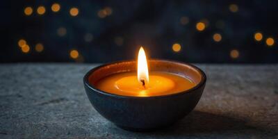 A candle is lit in a small bowl on a stone ledge. photo