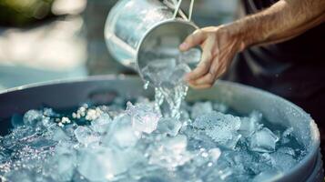 A man pouring buckets of ice cubes into a tub filled with water creating a refreshing and rejuvenating ice bath photo