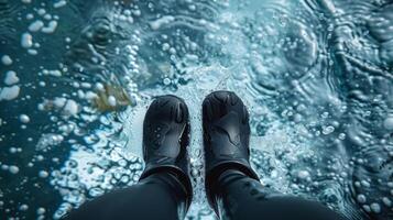 A persons feet are completely encased in neoprene dive boots which provide warmth and protection during cold water swims photo