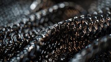 The camera zooms in giving us a birds eye view of the tightly woven fibers that make up the complex web of the engine belt. The fibers are black and shiny reflecting the light and givin photo