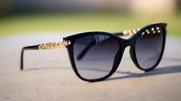Closeup of a stylish pair of cateye sunglasses with black frames and gold chain detailing on the sides. photo