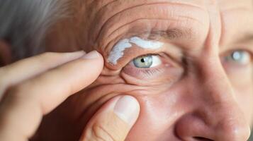 Closeup of an older person applying a rejuvenating eye cream to combat fine lines and wrinkles. photo