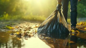 Closeup of a garbage bag being by a volunteers hand, after picking up litter around a local pond. photo