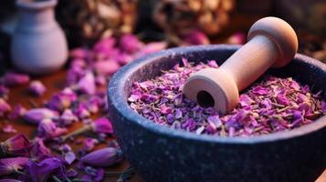 Closeup of a mortar and pestle crushing dried rose petals and lavender buds for a DIY facial toner. photo