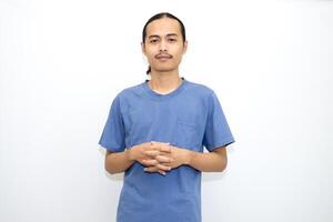 Smiling Asian man wearing dark blue t-shirt standing with crossed fingers and facing forward. isolated in white background photo