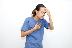 Asian man wearing blue t-shirt is feeling sick or unwell. holding his forehead. isolated in white background photo