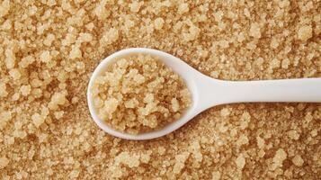 Overhead shot of brown sugar crystals and a white spoon. photo