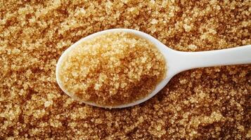 view of raw brown sugar lumps alongside white spoon photo