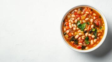 White bean and vegetable soup served in a white bowl on a wooden table. photo