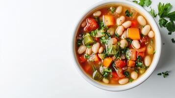 A white bowl filled with white bean and vegetable soup on a wooden surface. photo
