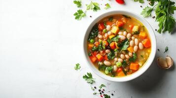 A white bowl filled with white bean and vegetable soup on a wooden surface. photo
