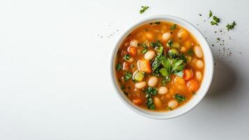 White bean and vegetable soup served in a white bowl on a wooden table. photo