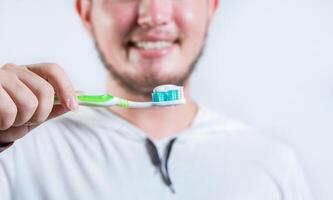 Hand of man showing toothbrush with toothpaste isolated. Close up of hands holding brush with toothpaste photo