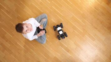 top view boy sitting on the floor, controls toy rc car with a remote control video