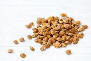 A pile of apricot pits on a light background. View from above. Vitamin B 17. Healthy food. photo