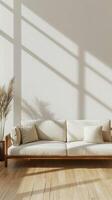 a minimalist-style living room with a beige sofa adorned with decorative pillows, set against a wall and wooden floor, offering a bright color background ideal for artwork or product displays. photo
