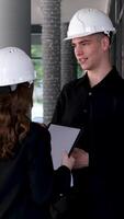 Female carpenter apprentice with her colleague. Guy and girl at a construction site, builders foreman video