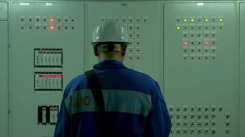 Work at the factory.Clip. A man in a blue suit and a white helmet is trying to open special electrical equipment for work. video