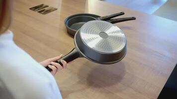 The woman raised the pan. ACTION. The cook holds a frying pan in his hand and puts it on the table. The man picked up a frying pan from the table and put it on the table video
