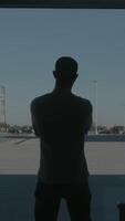 Silhouette of a businessman back overlooking the parking space behind the window. HDR. Rear view of a young man standing in front of panoramic window inside the business center. video