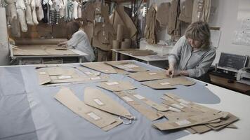 Tailors are busy working in a sewing workshop surrounded by pattern pieces and fabrics video
