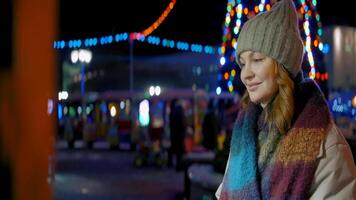Woman in the city street with Christmas illumination. Action. Female in warm clothes looking at the shop window and smiling. video