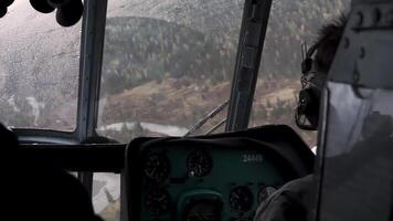 The view from the helicopter. Clip. The pilot controls the helicopter over a large green forest in calm weather . video
