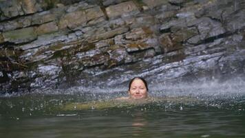 The girl dives in shallow water. CREATIVE. There is a lake near the stones. A long-haired man bathes in a pond. A plump girl dives in a pond video