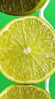 Close up of lime fruits being covered by toxic white liquid paint isolated on a green chroma key background. Stock clip. Concept of ecology and food waste. video