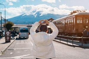 Woman tourist with Fuji Mountain at Kawaguchiko train station, happy Traveler sightseeing Mount Fuji in Yamanashi, Japan. Landmark for tourists attraction. Japan Travel, Destination and Vacation photo