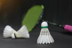 white shuttlecock on black background, blurred badminton racket and white shuttlecocks background. soft and selective focus. photo