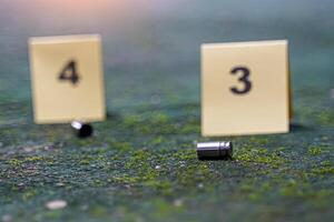 Bullet casings fall on cement floor and blurred background of evidence number sign at shooting scene. Concept of investigation, forensics, evidence, forensic science. photo