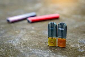 Electronic cigarettes on the cement floor and blurred backgrounds of various types of cigarettes, concepts of types of cigarettes, harms and dangers, addictive substances photo