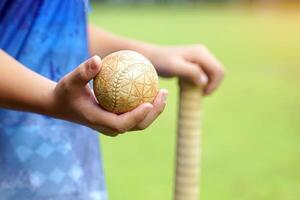 Asian boy players hold clicket ball in hand while practicing for the first time on the grass field. photo