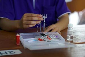 Asian school children conduct science experiments with kits Electrolysis, which is a method of electrically separating solutions to separate hydrogen and oxygen gases from water. photo