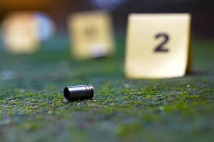 Bullet casings fall on cement floor and blurred background of evidence number sign at shooting scene. Concept of investigation, forensics, evidence, forensic science. photo