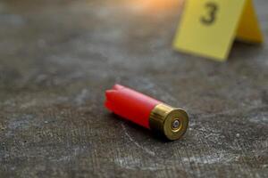 Bullet casings fall on cement floor and blurred background of evidence number sign at shooting scene. Concept of investigation, forensics, evidence, forensic science. photo