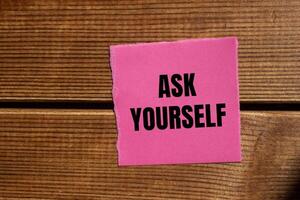 Ask yourself message written on ripped torn pink paper piece with wooden background. Conceptual ask yourself symbol. Copy space. photo