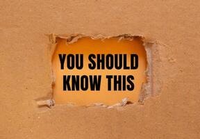 You should know this message written on ripped torn cardboard paper with orange background. Conceptual you should know this symbol. Copy space. photo