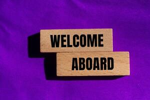 Welcome aboard message written on wooden blocks with purple background. Conceptual welcome aboard symbol. Copy space. photo