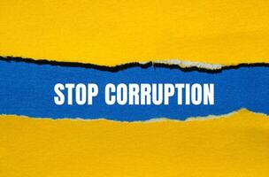 Stop corruption message written on ripped torn yellow paper with blue background. Conceptual stop corruption symbol. Copy space. photo