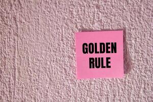 Golden rule message written on pink paper on concrete wall background. Conceptual golden rule symbol. Copy space. photo
