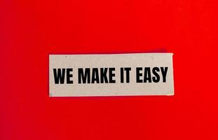 We make it easy message written on paper piece with red background. Conceptual we make it easy symbol. Copy space. photo
