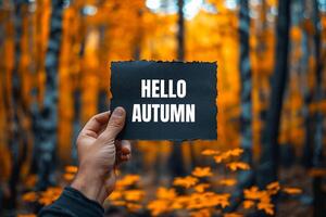Hello autumn message written on black ripped torn paper with nature background. Conceptual hello autumn symbol. Copy space. photo